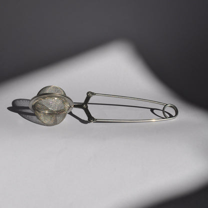 Metallic tea infuser on a dark background