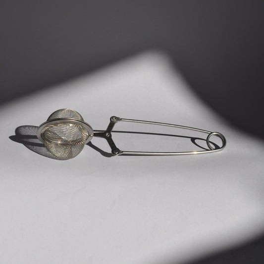 Metallic tea infuser on a dark background
